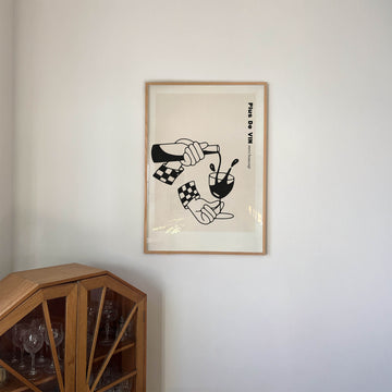 Framed black and white illustration of a hand pouring red wine into a glass with the text “More Wine Please” – bold kitchen wall art print from EDGE Wall Art