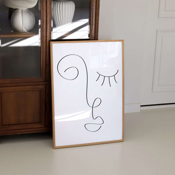 Minimalist abstract line art of a dreamy face with a swirl and closed eye. Black line on neutral background – modern whimsical face print from EDGE Wall Art Australia.